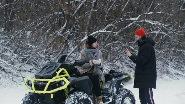 Young Couple Posing with ATV Quad Bike in Winter Forest