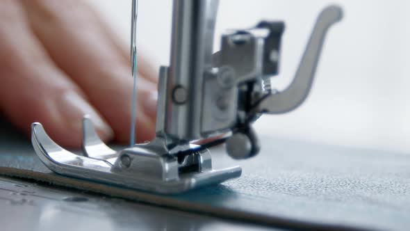 A seamstress works on a sewing machine. Close-up of a needle and thread. Clothes designer. Tailor.