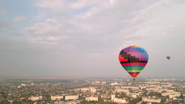 Colorful Hot Air Balloons Flying Over Buildings in Small European City at Summer Sunset, Aerial View