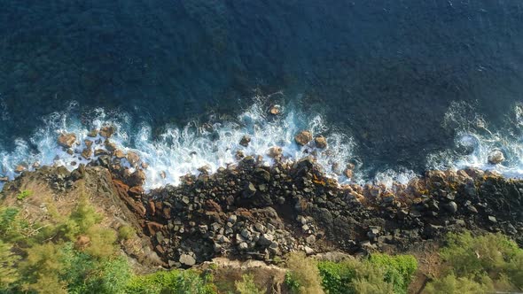 Birds Eye View of a Rocky Beach with Waves Crashing Against The Rocks