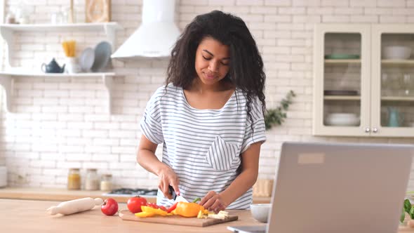 Charming Biracial Woman Watching Cooking Video Tutorial on the Laptop