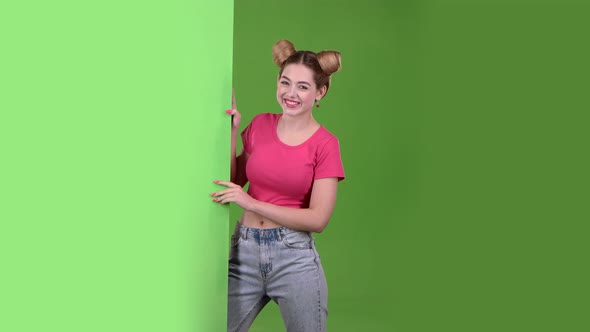 Girl Peeks Out From Behind a Green Board and Shows a Ok. Green Screen. Slow Motion