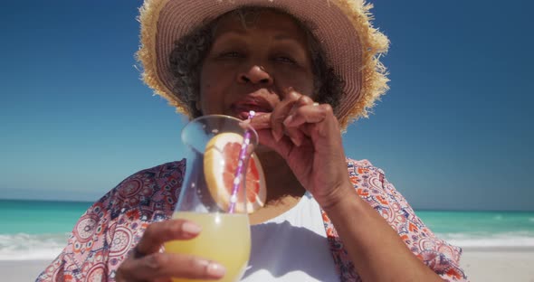 Senior woman drinking a cocktail at the beach