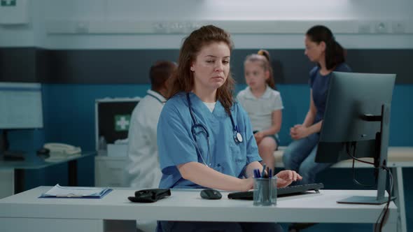 Portrait of Medical Assistant Using Computer to Work on Appointment