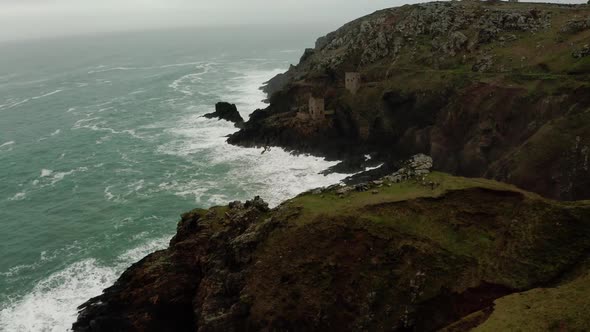 Aerial pan along the rough coastline of Cornwall, England, revealing ruins of the tin mines, part of