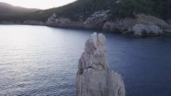 Smooth drone orbit of Benirra's rock tip at sunrise. The shot slowly pan up and tilt down to reveal