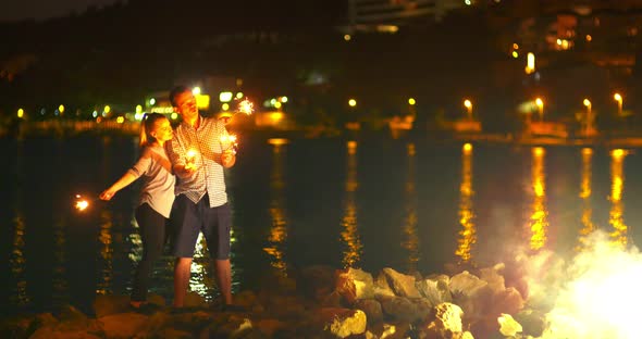 Couple Holding Sparklers at Seashore