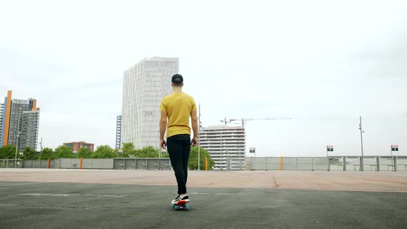 Young Attractive Trendy Man skateboarding fast under a solar panel on a morning sunny day with an ur