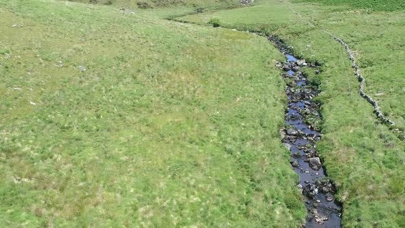 Wide shot aerial shot tracking forward in a birdseye view over a river before tilting up to reveal t