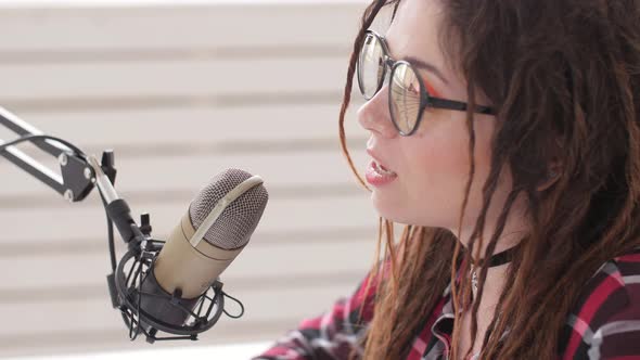 Podcasting and Radio Concept. Radio Host Young Woman in the Studio in Front of a Microphone