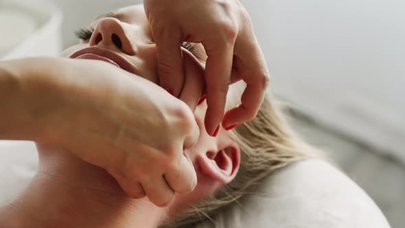 Beautician cosmetologist makes lifting face massage, pinch and roll technique