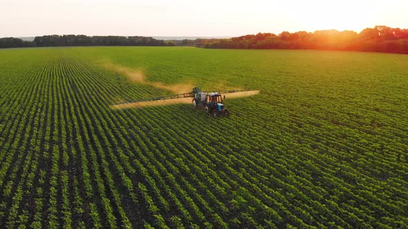 Aerial View of Farming Tractor Spraying on Field with Sprayer Herbicides and Pesticides at Sunset