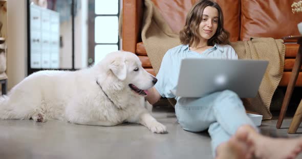 Woman with a Dog and Laptop at Home