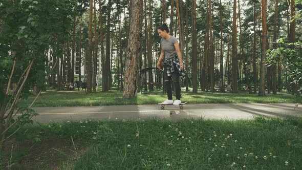 Female learning to ride on skateboard in park. Young happy girl 