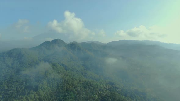 Aerial panorama Menoreh hills overgrown with tropical forest seen though clouds