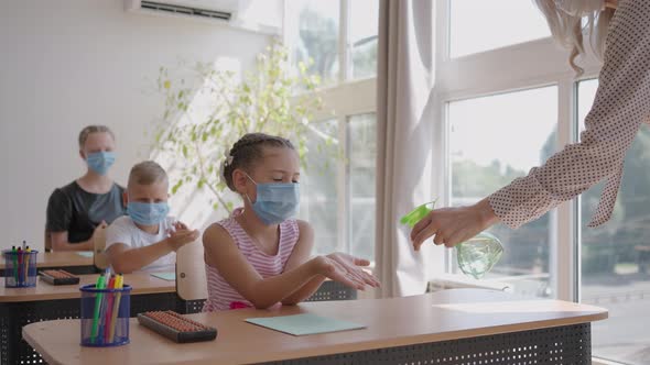 The Teacher Treats the Hands of an Antiseptic Girl in the Classroom at School Before Class