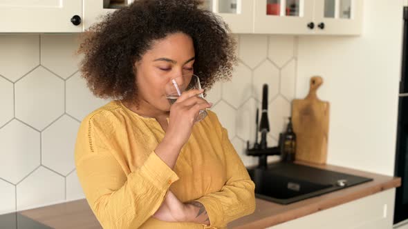 Curly Cheerful AfricanAmerican Woman Drinking Glass of Fresh Water