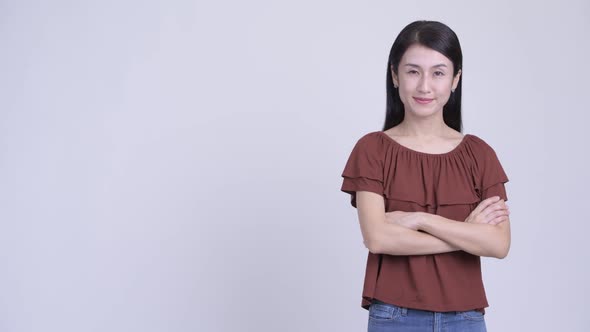 Profile View of Happy Beautiful Asian Woman Looking at Camera with Arms Crossed