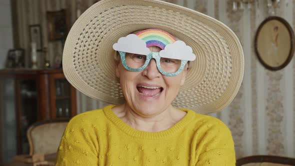 Close Up Portrait of Old Lady with Funny Glasses with Rainbow Looking at Camera Laughing and Smiling