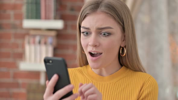 Portrait of Beautiful Young Woman Celebrating Success on Smartphone