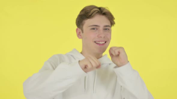 Young Man Dancing in Joy on Yellow Background