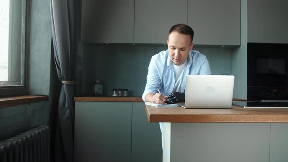 Serious man programmer with artificial prothesis hand looks at laptop display