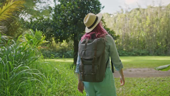 Beautiful Traveler Woman with Pink Hairstyle Walking By Scenic Botanical Garden