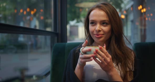 The Girl Is Sitting in a Cafe on the Veranda