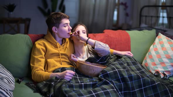 A young guy and his girlfriend are watching TV together in the evening