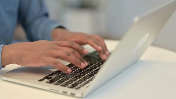 African Man Typing on Laptop Keyboard Close Up