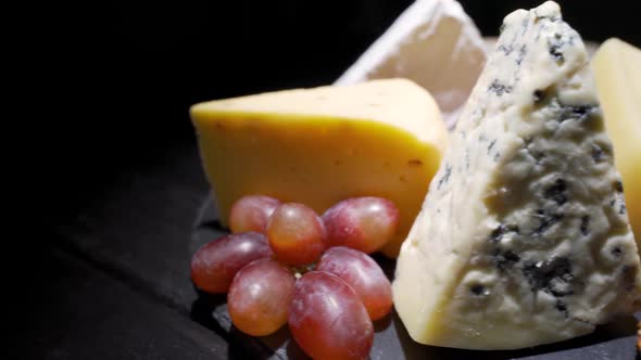 Pieces of Different Varieties of Cheese on a Black Wooden Table Closeup