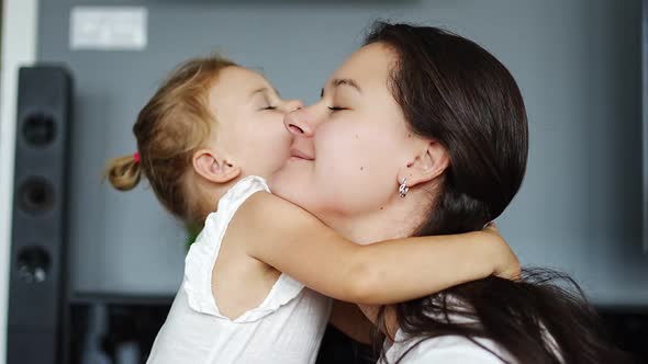 Little Girl Hugs Happy Laughing Mum at Home