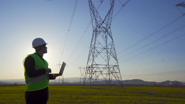 Engineer working in front of electric poles.