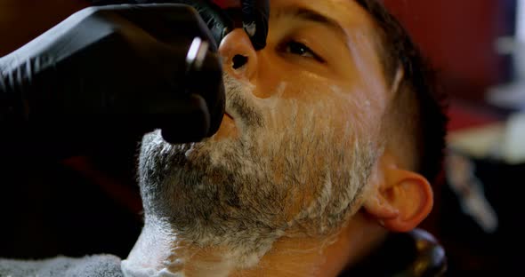 Male barber shaving a clients beard 