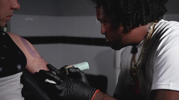 Cinematic Slow Motion Shot of a Tattoo Artist Creating Body Art at the Tattoo Studio