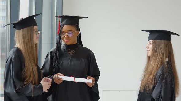 Three Female Students of Different Races with a Diploma in Their Hands