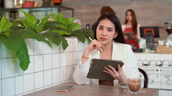 Thoughtful business woman thinking over future business plan at coffee shop, taking notes in tablet