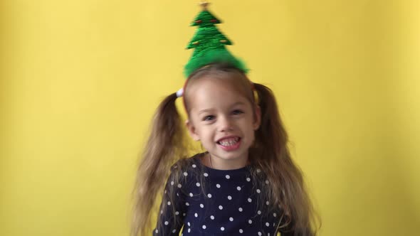 Portrait Emotion Cute Happy Preschool Baby Girl With Ponytail And Christmas Tree on Head Looking On