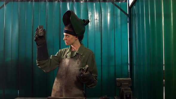 Female welder examining a piece of metal