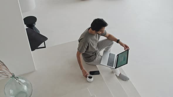 Man Using Laptop on Stairs at Home