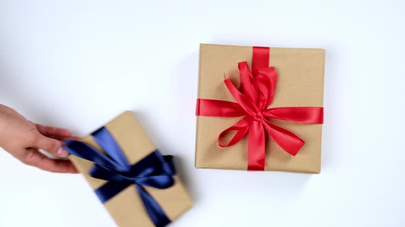 female hand puts gifts packed in brown kraft paper on a white table