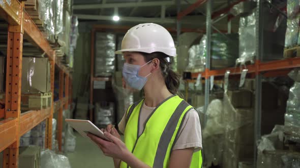 A Female Supervisor Wearing a Safety Vest Hard Hat and Face Mask During an Inspection at a Factory