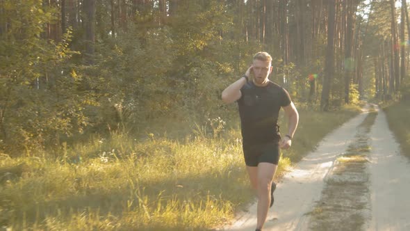 Muscular Man in Sport Outfit Running at Green Forest