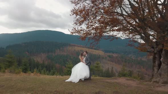 Lovely Young Newlyweds Bride and Groom Embracing Making a Kiss on Mountain Slope Wedding Couple