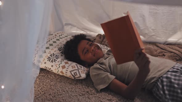 Boy Reading Book on Floor at Night