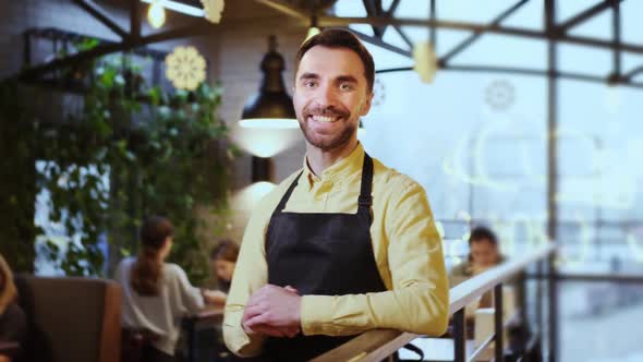 Portrait of Young Man Wearing Apron Standing in a Coffee Shop