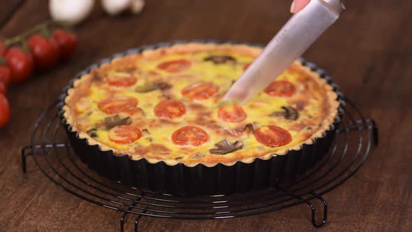 Cutting homemade quiche lorraine with chicken, mushrooms and cheese. French cuisine.