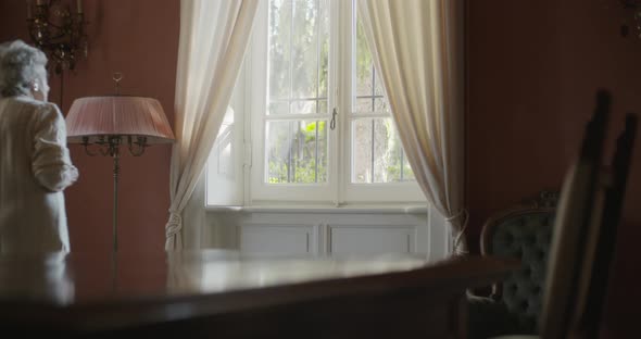 Senior Grandma Woman Walking Near Window Looking Outside