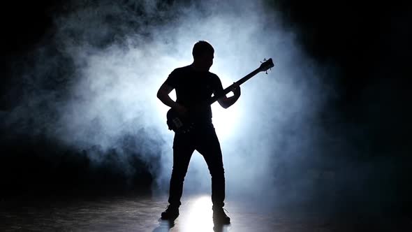 Silhouette Bass Guitarist Man in Smoke, Slow Motion, Black Background