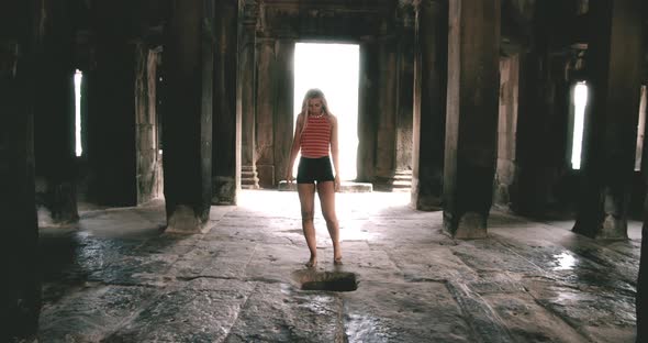 A Wide Shot of Blonde Female Model Dancing Barefoot Inside a Cambodian Temple